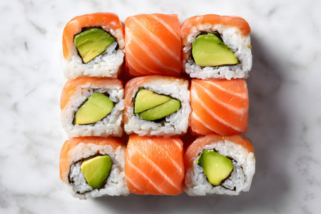 A colorful selection of sushi rolls features salmon, avocado, and cucumber arranged nicely on a marble surface. The vibrant colors make the dish inviting and appetizing.の素材