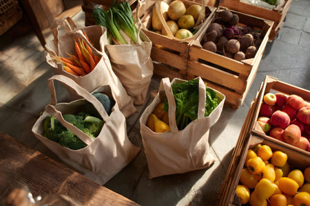 A variety of colorful vegetables and fruits are arranged in woven baskets on a wooden table. The sun casts warm light, highlighting the freshness and natural beauty of the produce.の素材