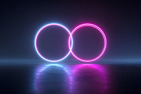 Two glowing circles, one in blue and one in pink, intersect in a dark setting. The neon lights reflect on the smooth surface beneath, creating a vibrant effect.の素材