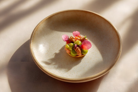 A beautifully crafted gourmet dessert sits in a round, neutral-toned plate. The dish features colorful garnishes, showcasing artistic culinary skill. Soft shadows enhance the elegant presentation.の素材