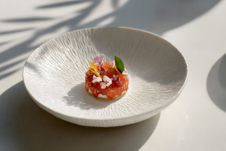 A beautifully crafted gourmet dessert sits in a round, neutral-toned plate. The dish features colorful garnishes, showcasing artistic culinary skill. Soft shadows enhance the elegant presentation.の素材