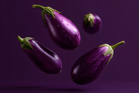 Vibrant eggplants are suspended in mid-air against a rich purple background, showing their smooth skin and unique shapes, adding a modern touch to kitchen decor.の素材