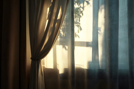 Soft sunlight filters through light curtains, creating a warm atmosphere in a room as day transitions to evening. The colors of the sunset enhance the serene vibe.の素材