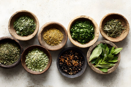 Bowl arrangement of different herbs and spices on a white surface in a kitchen settingの素材
