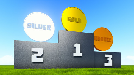 Victory rostrum on the green grass with a golden, silver and bronze medals on top の写真素材