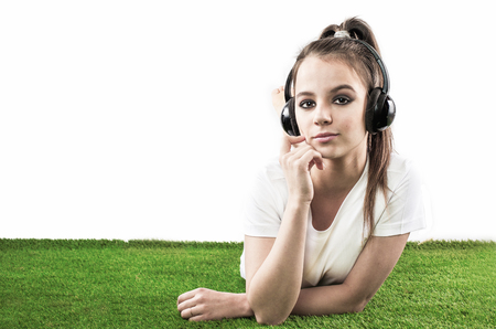 Girl listening to music streaming with headphones in summer on a meadow. White backgroundの写真素材