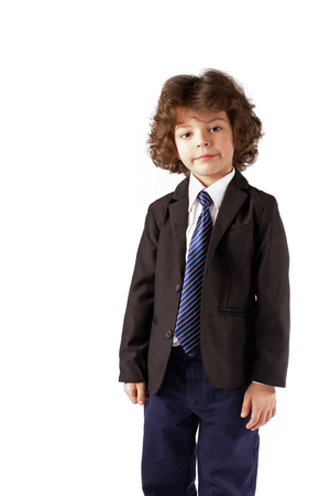 Cute curly boy stands and looking thoughtfully into the camera. White background.の写真素材