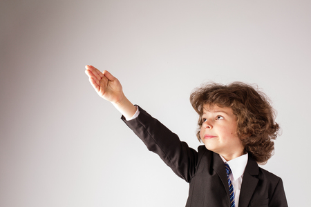 Funny curly boy raised his hand up. Gray background.の写真素材