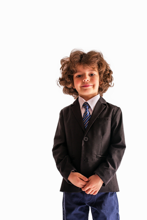 Pleased Curly boy looks at the camera in a business suit. White background.の写真素材