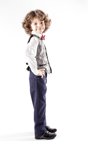 Cute curly boy stands sideways to the camera and looking into the camera. Full length. White background.の写真素材