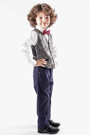 Cute curly boy stands sideways to the camera, and turning his head looking at the camera. Full length. White background.の写真素材