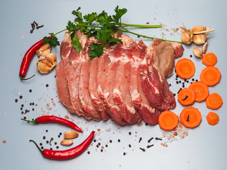 Chunks of raw meat for barbecue and spices lie on a board.の写真素材