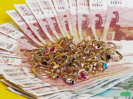 Placer gold jewelry with precious stones is on the banknotes. Yellow background.の写真素材