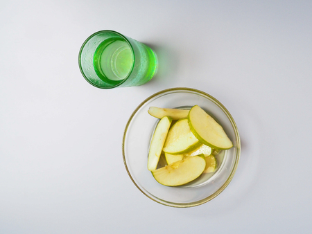 Sliced green apple lies in a plate with honey. It is worth a glass of water. View from above.の写真素材