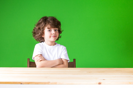 Curly boy with his arms crossed, smiling looks into the camera. Close-up. Green background.の写真素材