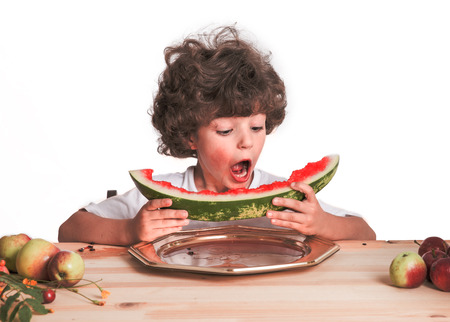 Little curly boy eats large ripe watermelon. White background. Close-up.の写真素材