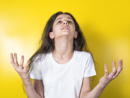 Pretty little girl in a white shirt with a thankful staring at the sky deep in her dreamsの写真素材