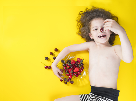 Cute boy child eating healthy organic food, fresh fruit.Yellow background with space for text or image.の写真素材