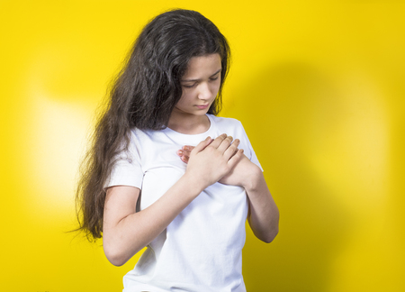 A young woman holds her hands on her chest .の写真素材