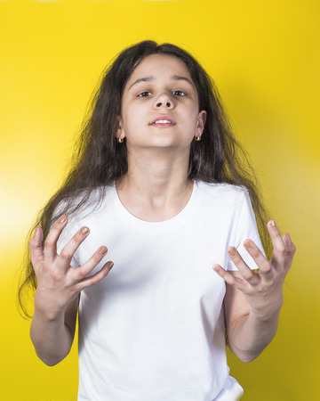 Pretty little girl in a white shirt with a thankful staring at the camera in her dreamsの写真素材