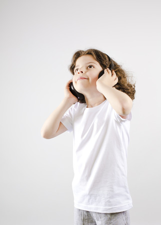 Music and technology concept.Caucasian little boy with headphone on gray backgroundの写真素材