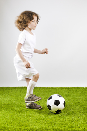 Boy with soccer ball on a gray background.の写真素材