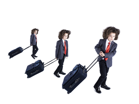 Collage. Little cute curly boy dressed in a business suit wheels suitcase isolated on white backgroundの写真素材