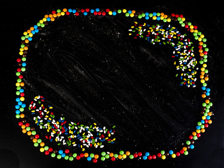 Sunflower seeds frame. Sweets in color glaze. Black backgroundの写真素材