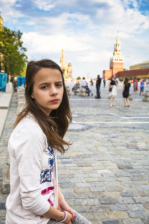Sad young lady sitting on the red Square in Moscow and looking at the camera.の写真素材