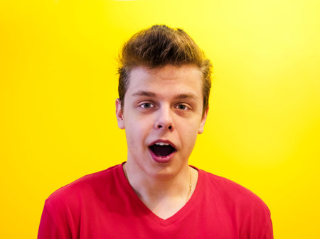 Portrait of a young man with a shocked facial expression isolated on a yellow background