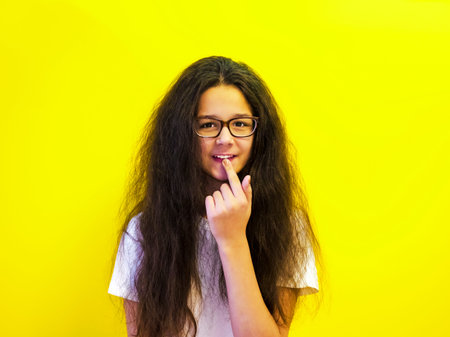 A teenager on a yellow background smiles and points a finger at her pinned forward tooth