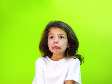 Shocked, surprised child fed up, bored or showing despair, Isolated on green.の写真素材