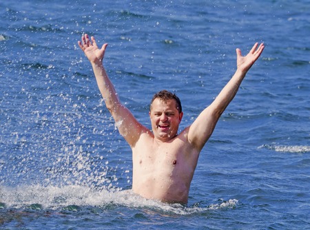 A nice man makes joy in the sea. Raised his hands up.の写真素材