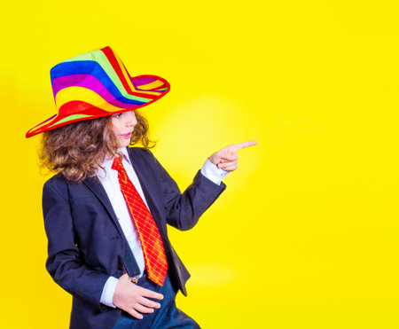 Young business man pointing and looking at a yellow background