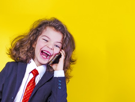 A small businessman is holding a phone for a conversation with a smile and happy, isolated on a yellow background. copy spaceの写真素材