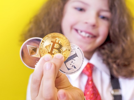 The Caucasian child holds bitcoin BTK , lithecoin LTC , etherum ETH in his hand, select the focus on the gold coin. Gold bitcoins digital virtual money , digital cryptococciの写真素材