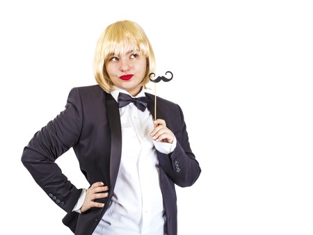 Elegant woman in a tailcoat with a black paper mustache on a stick on a white backgroundの写真素材