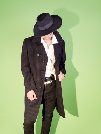 Young man gangster hides a gun under the belt of jeansの写真素材