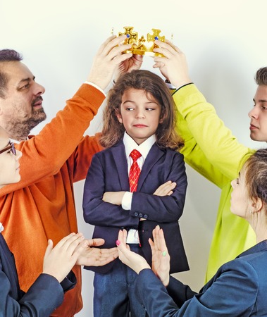 The hands of grown men wear a golden crown on a guys head in a business suit. Winner. Leader. A selfish man. The concept of the award ceremony.の写真素材