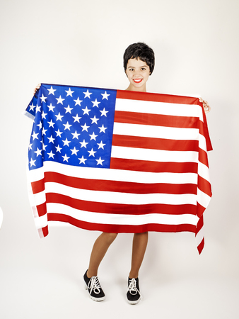 Happy young woman with the US flag. Image isolated on a light backgroundの写真素材