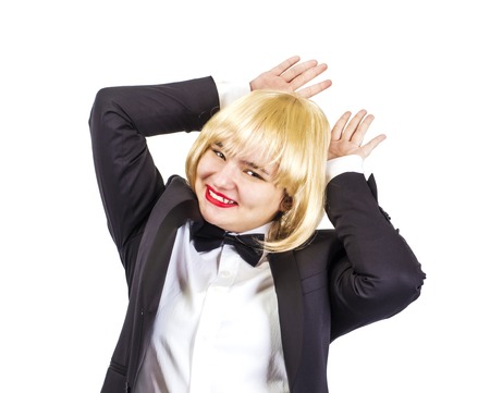 An image of a funny young fair-haired lady fooling around in the room, holding both her hands behind her head like rabbit earsの写真素材