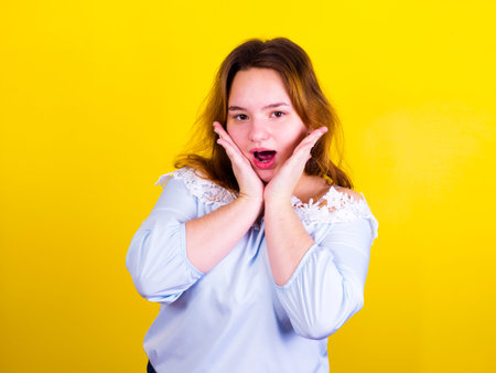 Scared plus size girl isolated on a yellow backgroundの写真素材