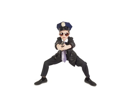 Boy in a tie and policeman's cap holding a gun in his hands, isolated on a white backgroundの写真素材