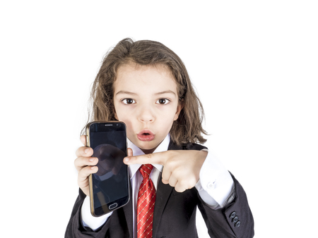 Dressed in a businessman clicks a finger on the smartphone screen. A boy in a business suit points a finger at important information on the phone screen.の写真素材