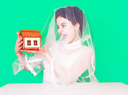 Beautiful bride brunette with a little wooden house as a symbol. A girl sitting at a table on a...
