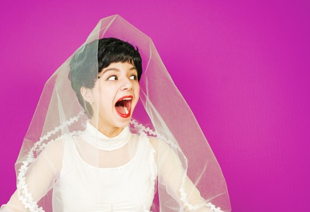 wow, no way. Portrait of amazed bride young woman in white dress and bridal veil against light blue pink background. Copy spaceの写真素材