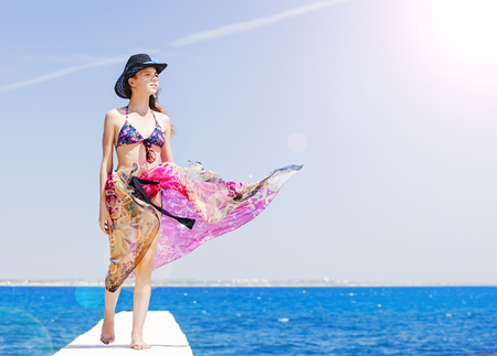 Portrait of a beautiful young woman looking away. Photo against the sky and sea.の写真素材