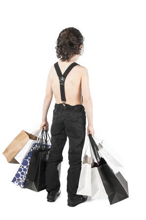 A curly-haired boy is standing with purchases back to the camera. White background.の写真素材
