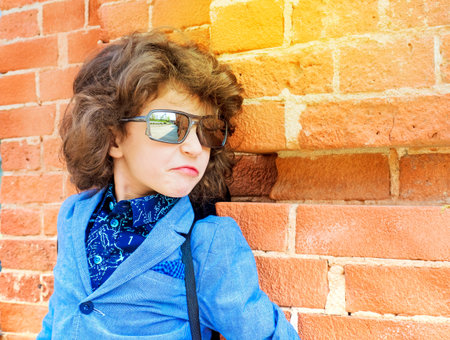 Cute little boy on brick wall background. Kids fashion concept
