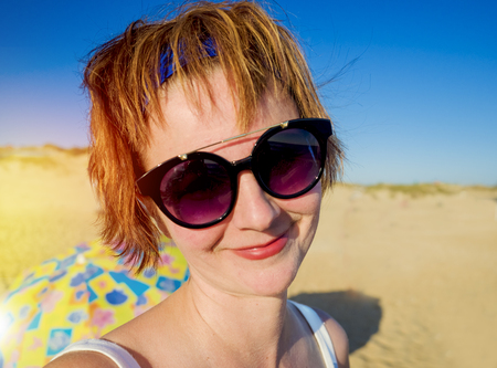Happy woman on the beach. Portrait of the positive red-haired woman closeup. Summer portrait on the beach. Young smiling woman outdoors portrait. Close. oceanの写真素材